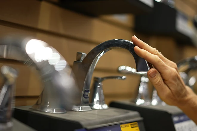 Hand touching a faucet for a bathroom