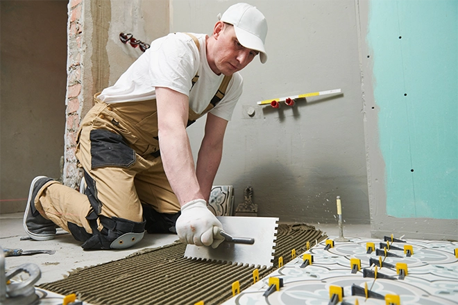 Contractor tiling a bathroom floor