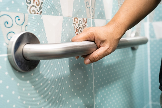 Hand holding grab bar in home bathroom
