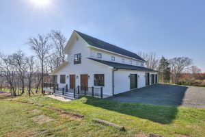 Large white barn with multiple doors and garages and floors