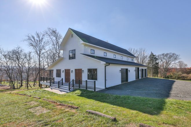 Large white barn with multiple doors and garages and floors
