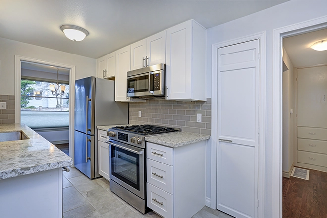 Modern kitchen with white cabinets and gray backsplash